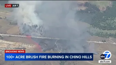 Firefighters are battling a large brush fire burning on a hillside near the 71 Freeway in Chino Hills.