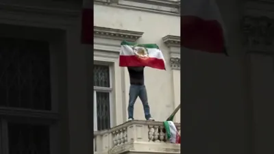 א פראטעסטירער רייסט אראפ די איראנער פאן פון די איראנע אמבאסאדע אין לאנדאן און לייגט ארויף די רעוועלוציע פאן