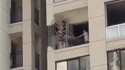 א איינוואוינער שניידט א זייל אין א 20 שטאקיגע כינעזישע געביידע.