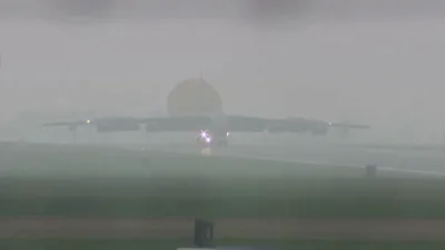 א שווערע אמעריקאנער באמבארדירער ניצט א פאראשוט צו לאנדן אויף בריטישער לופטבאזע.