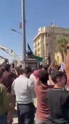 צערעמאניע אין 'פיעס סקווער': טויזנטער האלטן מיט ווי די סירישע פאן ווערט אויפגעהויבן אינעם לעצטן פעסטונג